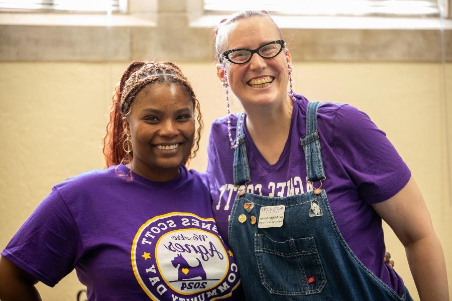 two people pose for a photo wearing purple shirts